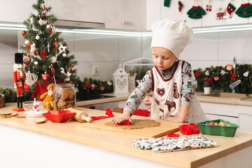 Little boy prepairing and decorating  gingerbreads in modern kitchen - kid at home in Christmas time