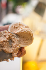 Serving hazelnut ice cream gelato in cup with paddle