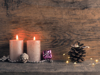 Candle of the second Advent burns, pine cones and Christmas decoration on wood