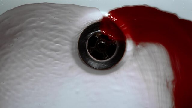 Closeup of Water Washing Dark Red Blood Into Sink Drain in Natural Light. Blood with water flows down the drain hole in the shower. Concept blood, blood pressure, pool of blood on the shower.
