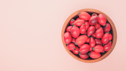 Rose hips in a wooden bowl. Top view. Fresh Rose hip berries. Place for text.