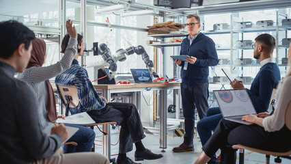 University Robotics Lecture: Teacher Explaining Engineering to Students by Using Robot Arm. Diverse Group of Young Engineers Programming Robotic Hand. Computer Science Higher Education Concept.