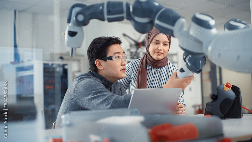 Aufkleber Asian Engineer Repositioning and Examining Robotic Arm with Middle Eastern Female Colleague In Robotics Development Laboratory. Research on Design, Operation and Performance of Robotic Mechanism.