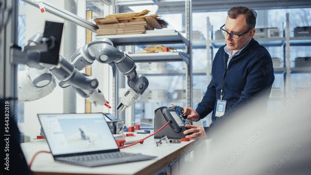 Poster Male Senior Developer Works on Engineering Project, Changes Robotic Hand Position with Lever. Empowered Engineer Doing Creative Project. Robotics and Automation for Facilities Concept.
