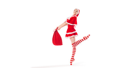 Dancing ballerina with a bag of gifts in her hands on pointe shoes in a Santa Claus costume...