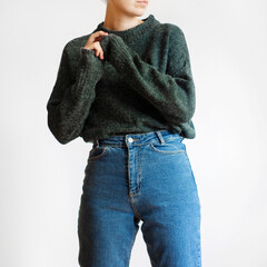 Woman wearing oversized green sweater and blue mom jeans isolated on white background