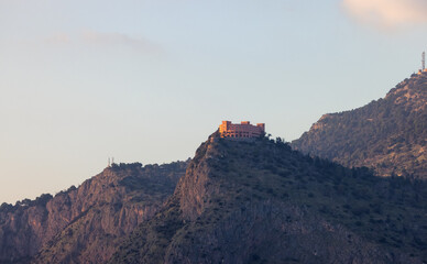 Fototapeta na wymiar Modern Building on top of a mountain in Palermo, Sicily, Italy. Sunny Sunset.