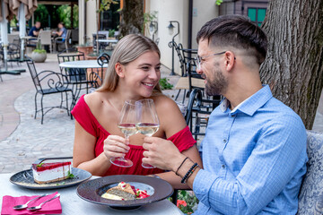 Romantic couple toasting with wine at lunch or dinner in a beautiful outdoor restaurant. Lifestyle, love, and relationships.	