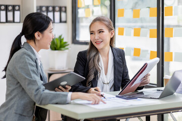 Two young asia business woman working together in office space, doing planning analyzing the financial report, business plan investment, finance analysis concept.