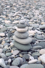 Fototapeta na wymiar Stone Cairn on Grey Pebble Sea Background. Rock Zen Sculpture