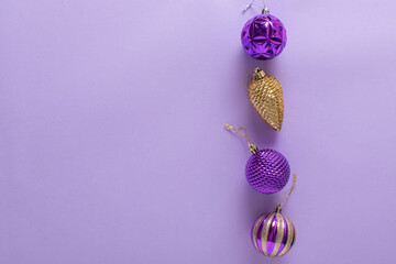 Christmas composition with purple Christmas tree balls and a golden cone on purple background.
