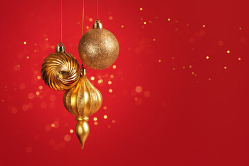 Christmas card with three golden balls decorations on red background with bokeh lights