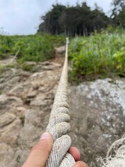 Male hand holds rope for climbing mountain slope at Cape Velikan, Sakhalin Island, Bottom view