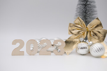 Christmas tree with golden bow, number 2023 and silver balls. Christmas background.