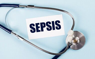 Stethoscope and white card with SEPSIS text on blue background. Medical concept.