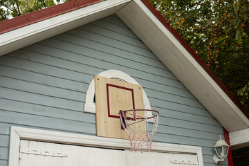 Basketball hoop on building. Sports equipment in yard.