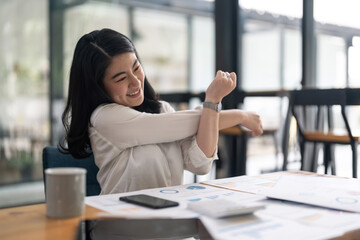 Young Asian Business Accountant woman stretching herself and relax while working hard