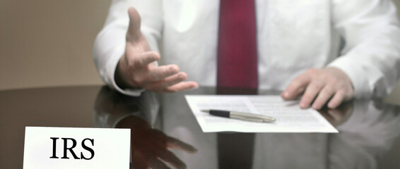 Business Man Businessman at Desk with Papers and Card Making Hand Gestures IRS Agent