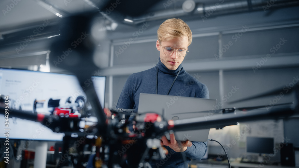 Poster Young Male Developer Programming on Laptop Computer. Working on a New Modern Drone Design in the Research Center Laboratory. People Creating Futuristic Unmanned Aerial Vehicle Concept.