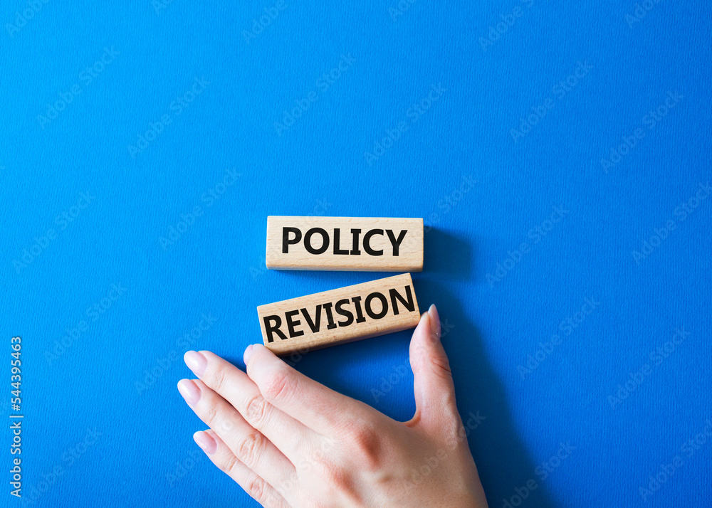 Sticker Policy revision symbol. Concept word Policy revision on wooden blocks. Businessman hand. Beautiful blue background. Business and Policy revision concept. Copy space