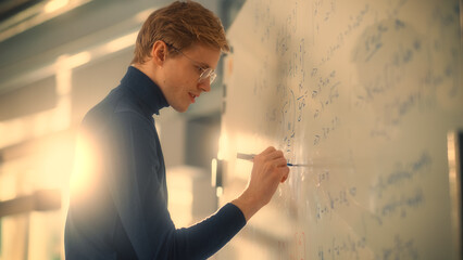 Young Male Scientific Researcher Writes Formula or Equation on Whiteboard In the University of...