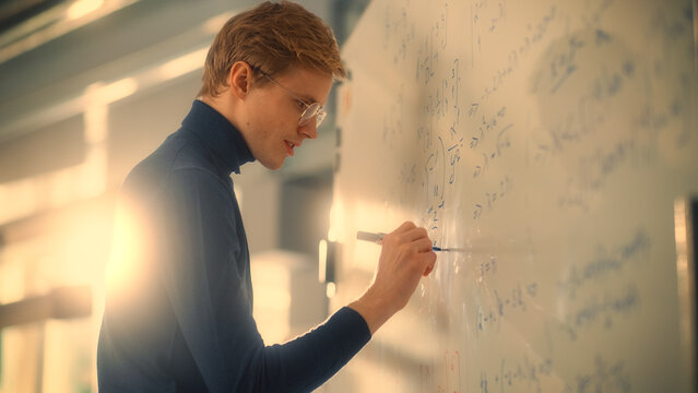 Young Male Scientific Researcher Writes Formula or Equation on Whiteboard In the University of Technology Modern Laboratory. Science and Research for Genetics or Technology Concept.