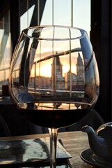 Fototapeta na wymiar A glass of wine with sunset and blurry cityscape in the background