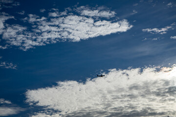 Naklejka na ściany i meble Blue sky with clouds and an airplane