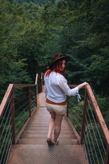 Woman traveler in Okatse Canyon in Georgia, standing on hanging metal pedestrian pathway trail...