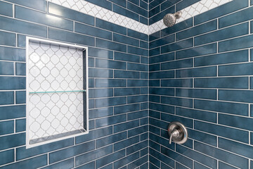 A blue subway tiled shower with a niche inlayed with arabesque shaped tiles.