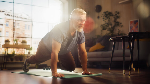 Strong Athletic Fit Middle Aged Man Doing Mountain Climber Exercises During Morning Workout at Home in Sunny Apartment. Healthy Lifestyle, Fitness, Recreation, Wellbeing and Retirement.