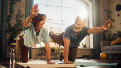 Happy Smiling Senior Couple Doing Gymnastics and Yoga Stretching Exercises Together at Home on Sunny Morning. Concept of Healthy Lifestyle, Fitness, Recreation, Couple Goals, Wellbeing and Retirement.