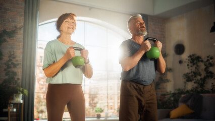Happy Senior Couple Doing Morning Exercises and Kettlebell Workout Together at Home in Sunny Living...