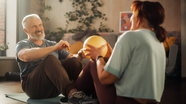Middle Aged Couple Doing Core Strengthening Exercises and Crunches Workout Together at Home in Sunny Living Room. Senior Man and Woman Motivate Each Other to be Healty.