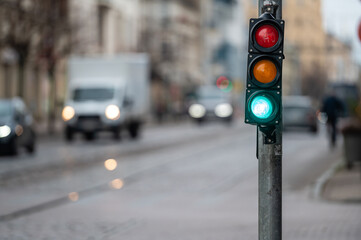 view of city traffic with traffic lights, in the foreground a semaphore with a green light, closeup