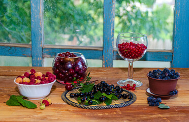 Blackcurrant berries on the table. Black currant with green leaves on a mat on a wooden table.