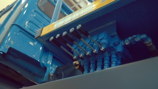 The block of hydraulic control valves of the new truck, which is responsible for the movement of the body, crane, winch, compaction of garbage. Shot in motion. Closeup