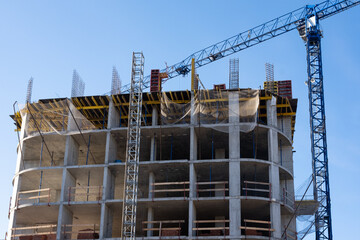 A construction site with a crane on a blue sky background. Construction of high-rise buildings