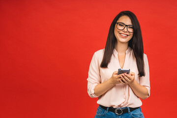 Photo of cheerful cute beautiful business young woman using mobile phone isolated over red background. Space for text.