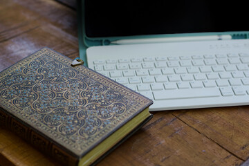 Tablet PC with keyboard, pencil and black screen and a beautiful notebook with and side closure. Material on a wooden table for remote working while traveling. Digital nomad concept.
