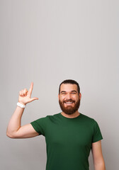 Fototapeta premium Vertical shot of a strong handsome man pointing up at the copy space above.
