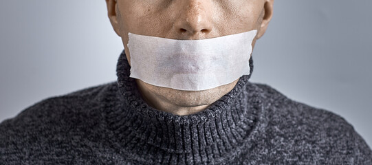 Man silenced with duct tape over his mouth. Photo with copy space.