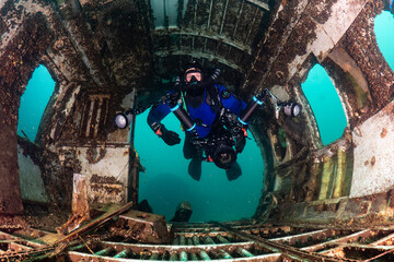 Scuba diver on a closed circuit rebreather and underwater camera swimming through an old aeroplane...