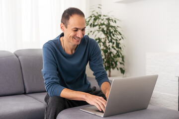 Young male tech user relaxing on sofa holding laptop computer mock up blank white screen. Man using modern notebook surfing internet, read news, distance online study work concept.