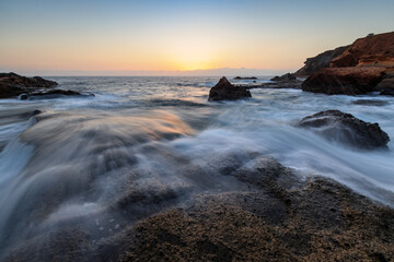 Obraz premium Rocky shore of the Atlantic Ocean at high tide at sunset