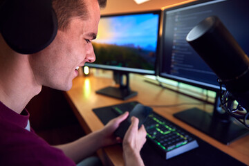 Close Up Of Man With Mobile Phone Gaming At Home Sitting At Desk With Multiple Monitors