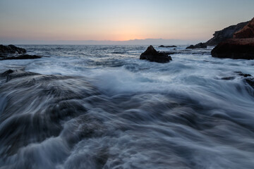 Rocky shore of the Atlantic Ocean at high tide at sunset