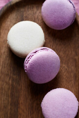 Pink and yellow macaroon cookies on wooden bowl