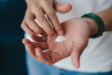 Closeup shot of man's hands holding and applying moisturiser cream. Skin care routine. Beauty treatment. Morning beauty routine. Health care.