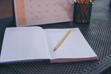 Planner write meeting agenda at Calendar book, work online at home. Diary for organizer to plan timetable, daily appointment, and management job at office desk. Planner book and Calendar 2023 Concept.